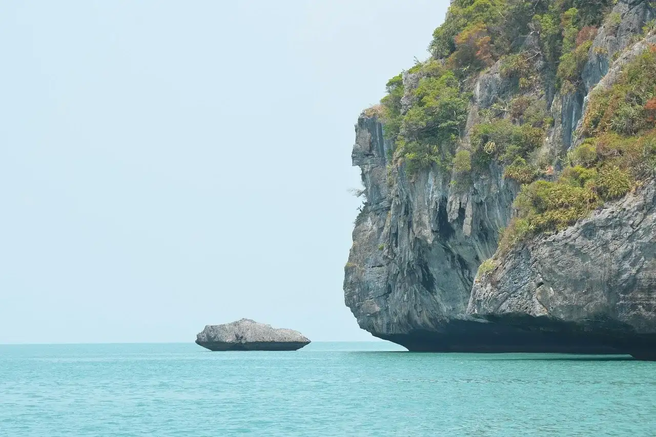 Scogliera calcarea che si alza dall'acqua turchese e calma di Ang Thong