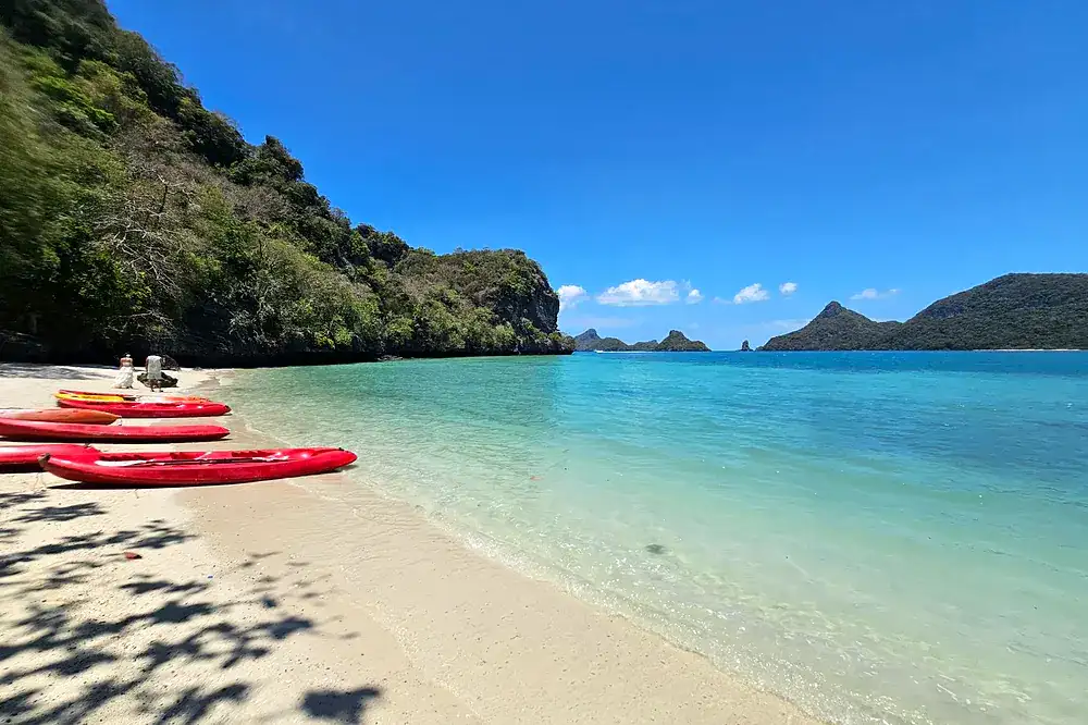 Red kayaks on a white sand beach