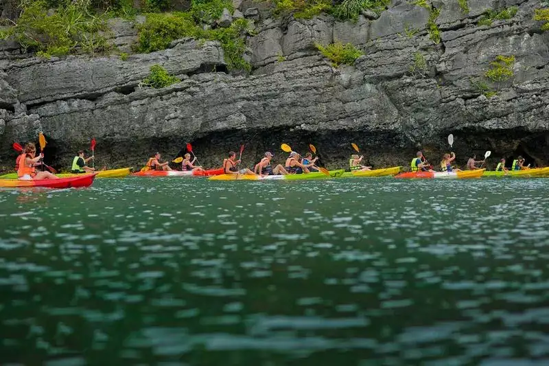 A line of kayaks under a limestone cliff